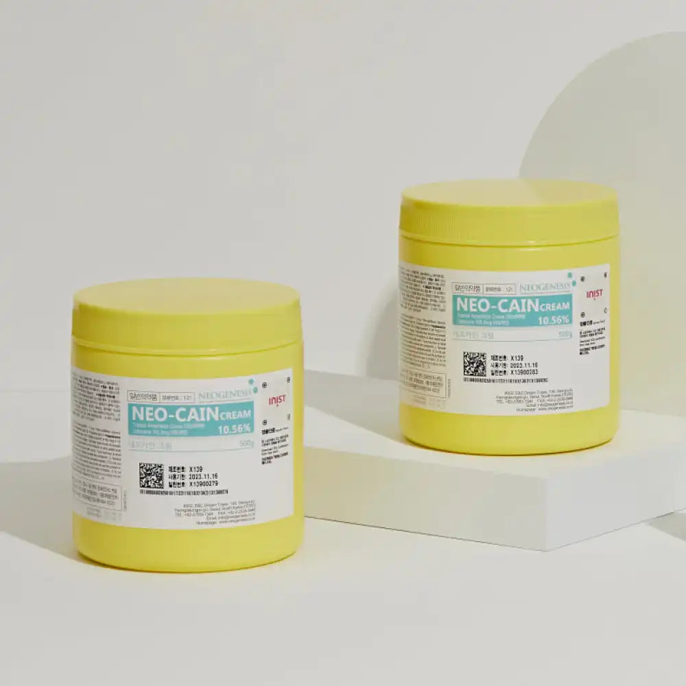 Two yellow containers of NEO-CAIN Cream 10.56% displayed on a white surface with a minimalistic background.